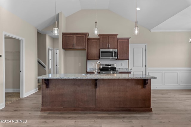 kitchen with sink, stainless steel appliances, light stone countertops, an island with sink, and decorative light fixtures