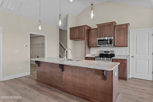 kitchen with appliances with stainless steel finishes, sink, a breakfast bar, and decorative light fixtures