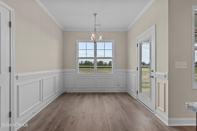 unfurnished dining area featuring crown molding, a chandelier, and light wood-type flooring