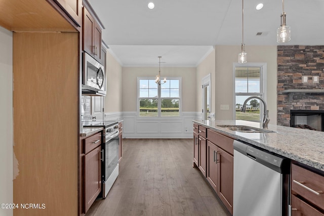 kitchen with pendant lighting, sink, light stone countertops, and appliances with stainless steel finishes