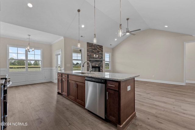 kitchen featuring sink, light stone counters, appliances with stainless steel finishes, an island with sink, and pendant lighting