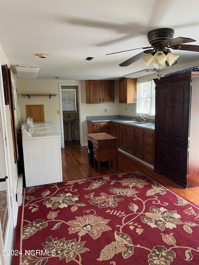 kitchen with dark wood-type flooring, independent washer and dryer, a sink, and a ceiling fan