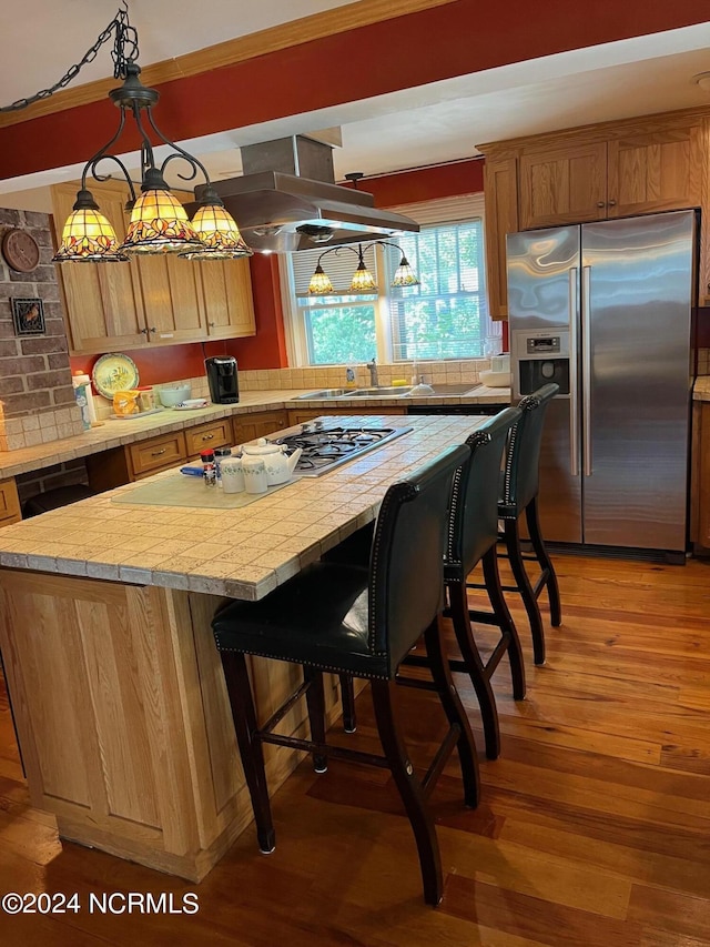 kitchen with light wood-style flooring, island range hood, a kitchen island, light countertops, and stainless steel refrigerator with ice dispenser