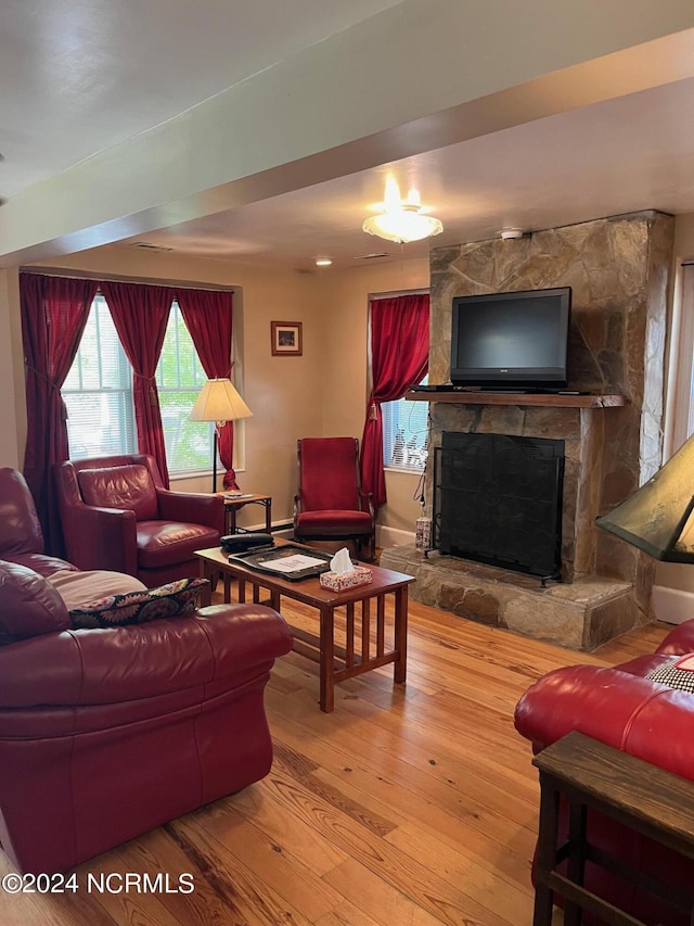 living room with hardwood / wood-style floors and a stone fireplace