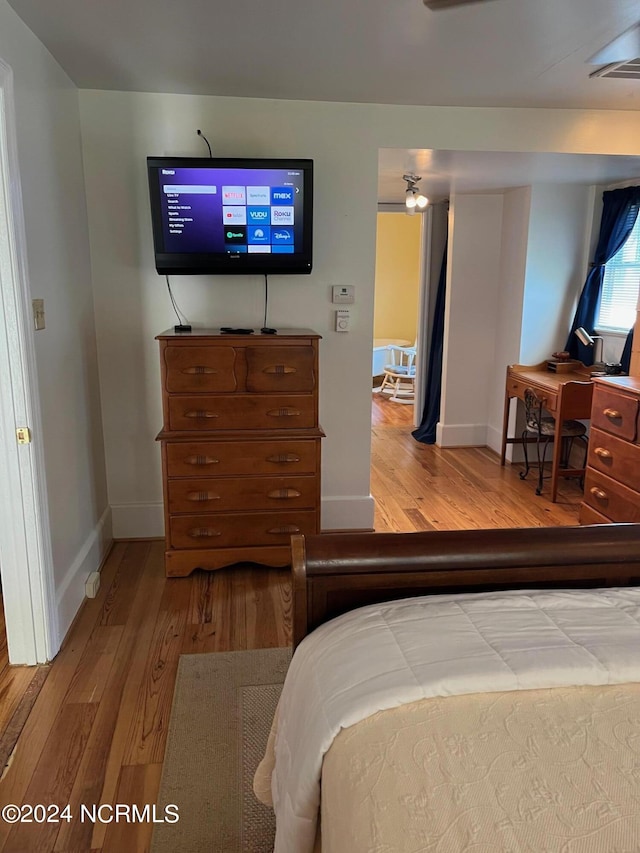 bedroom featuring wood finished floors, visible vents, and baseboards