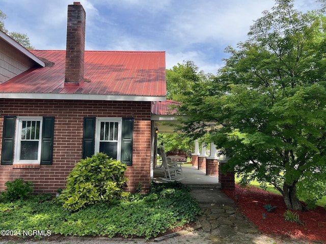 view of property exterior with metal roof, brick siding, and a chimney