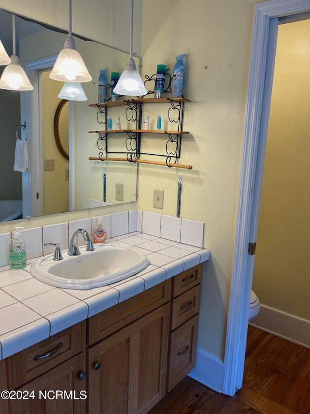 bathroom with toilet, baseboards, wood finished floors, and vanity