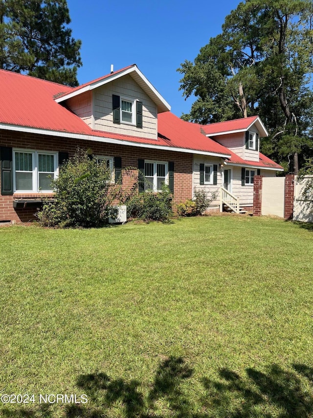 view of front facade featuring a front yard, brick siding, and fence