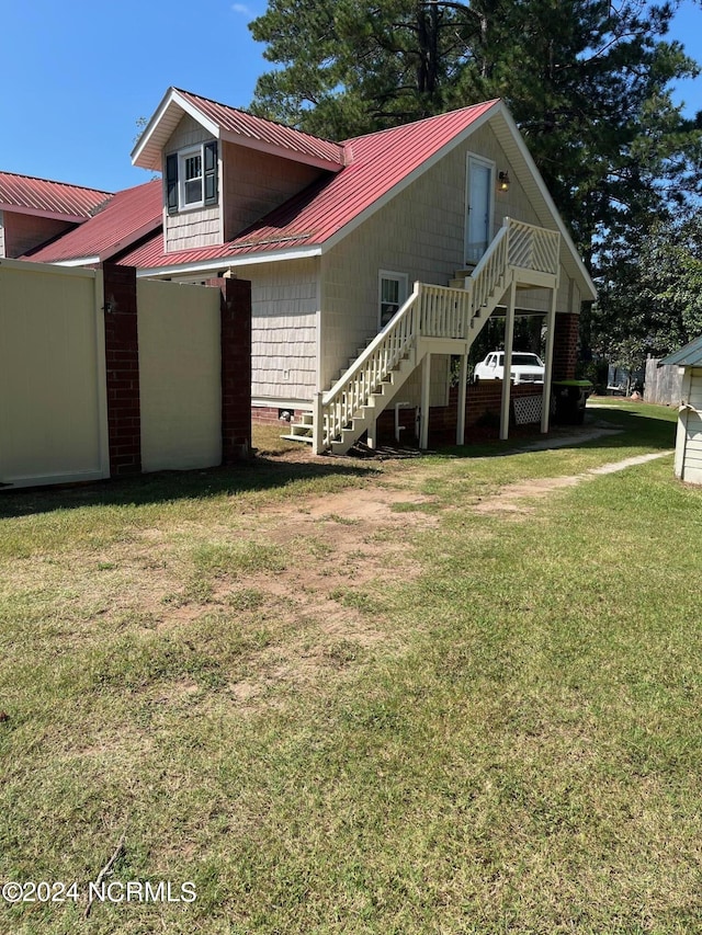 view of front of home with stairs, metal roof, and a front lawn