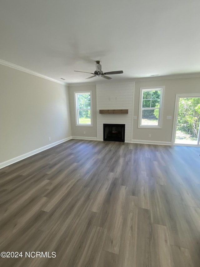 unfurnished living room featuring dark hardwood / wood-style flooring, a large fireplace, and crown molding