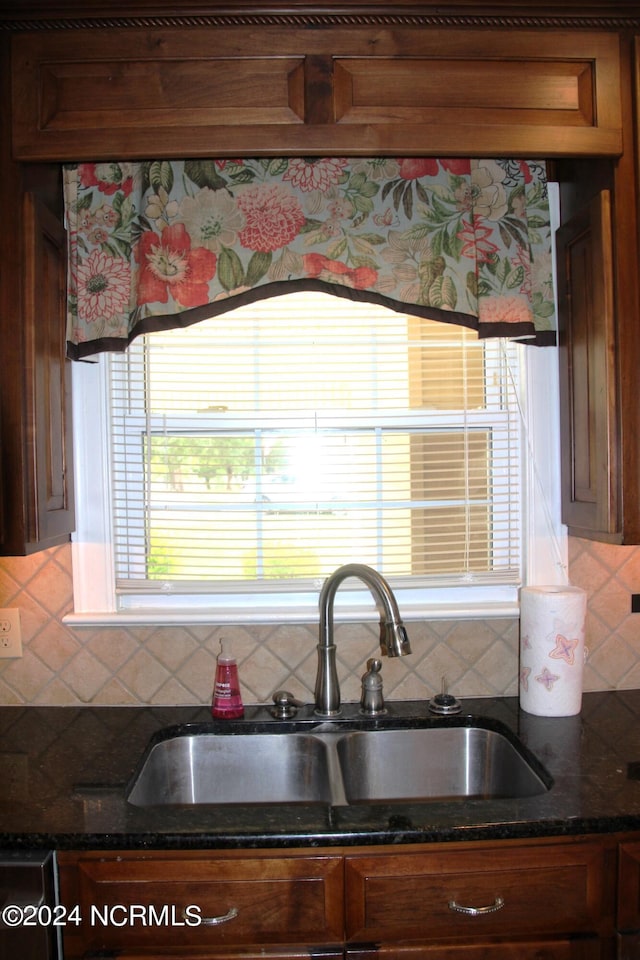 kitchen featuring dark stone countertops, tasteful backsplash, and sink