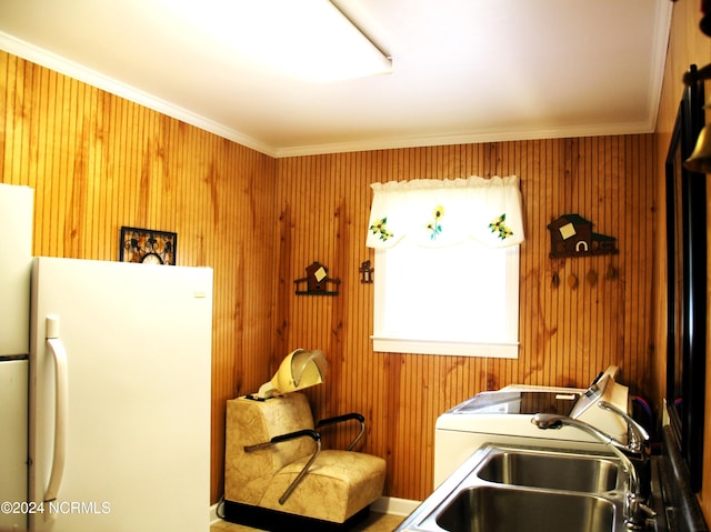 kitchen featuring sink, wood walls, crown molding, and white refrigerator