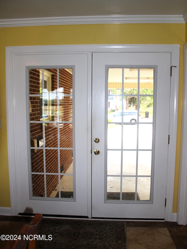 doorway featuring french doors, crown molding, and dark tile flooring