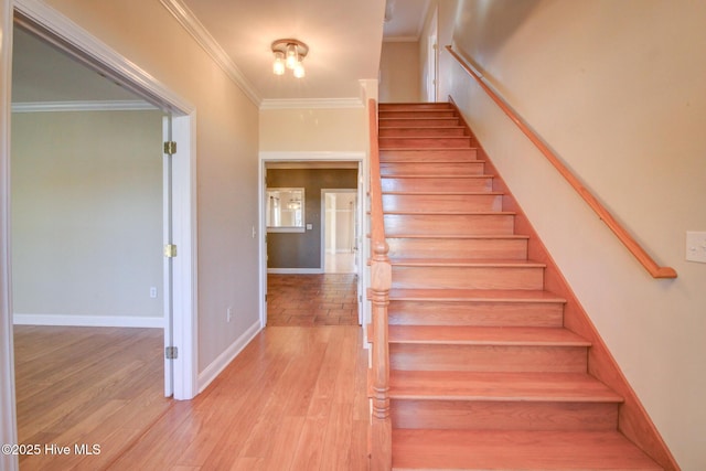 stairway featuring baseboards, ornamental molding, and wood finished floors