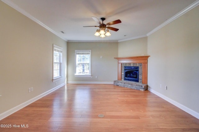 unfurnished living room with light wood-style floors, a brick fireplace, baseboards, and crown molding