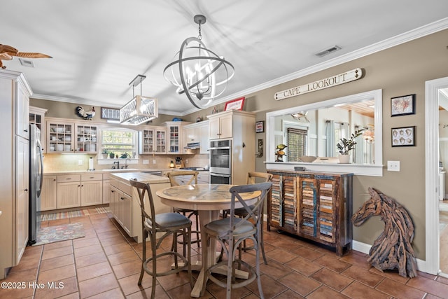 kitchen featuring crown molding, light countertops, visible vents, glass insert cabinets, and appliances with stainless steel finishes