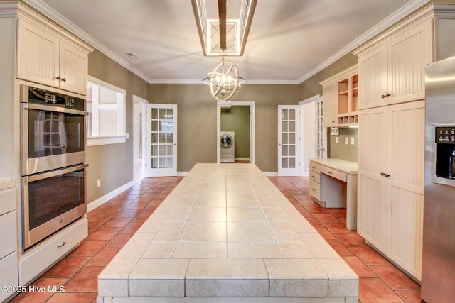 kitchen with tile counters, cream cabinetry, and appliances with stainless steel finishes