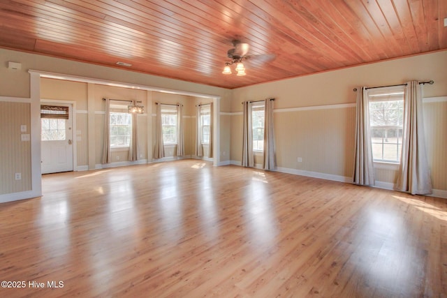 empty room with a ceiling fan, wood ceiling, a healthy amount of sunlight, and light wood-style flooring