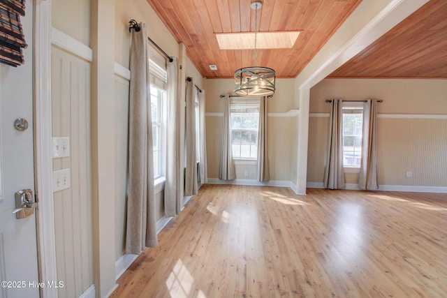 doorway with a notable chandelier, a skylight, wood ceiling, baseboards, and light wood-type flooring