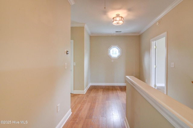 hallway featuring light wood finished floors, baseboards, and crown molding