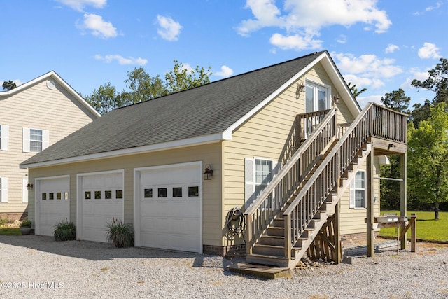 view of side of property featuring a garage, roof with shingles, and stairs