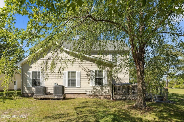 rear view of house featuring central AC unit, a deck, and a lawn