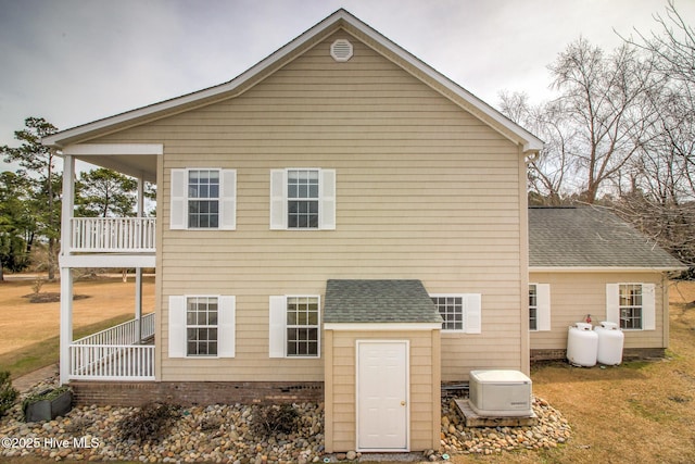 rear view of property featuring a shingled roof