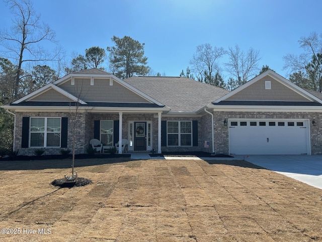 craftsman-style home featuring a garage, driveway, and brick siding