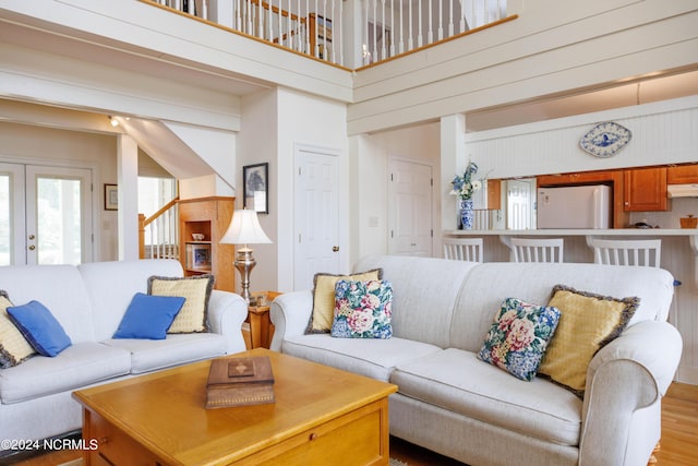 living room featuring french doors, a towering ceiling, and light wood-style flooring