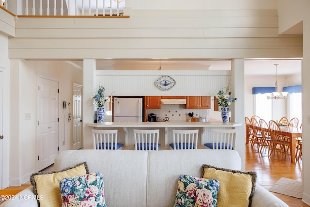 living room with ornamental molding, an inviting chandelier, and light wood-style floors