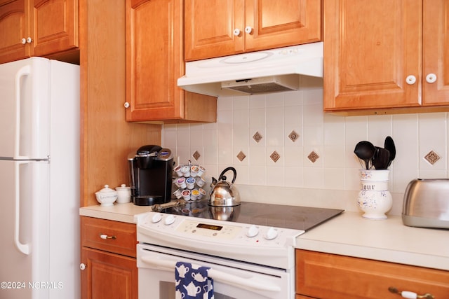 kitchen featuring brown cabinets, tasteful backsplash, light countertops, white appliances, and under cabinet range hood