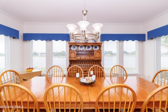 dining area with a chandelier, a water view, and crown molding