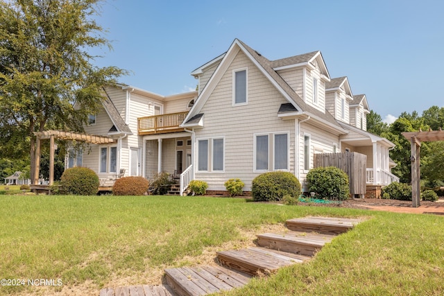 view of front of home with a shingled roof, a front yard, a balcony, and a pergola