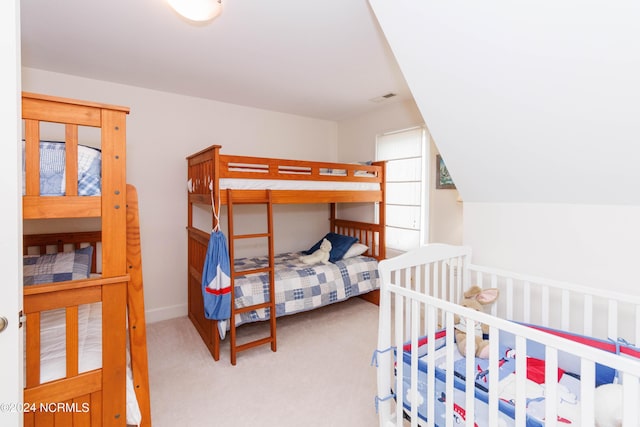 carpeted bedroom featuring lofted ceiling and visible vents