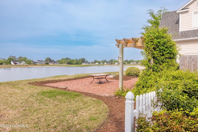 view of yard with a pergola, a patio area, fence, and a water view