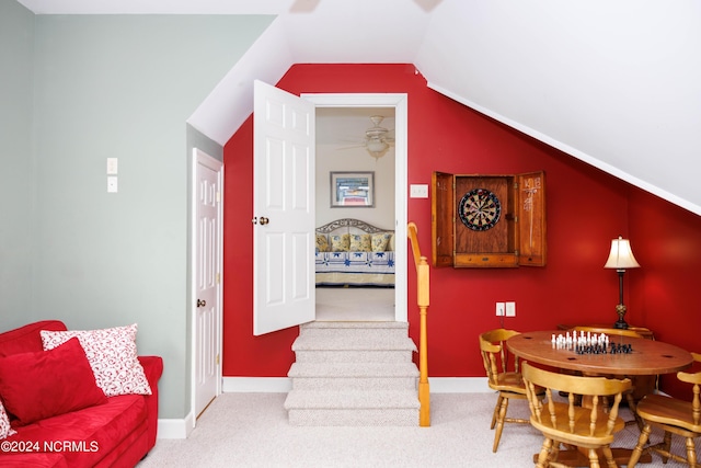 interior space featuring light carpet, baseboards, ceiling fan, stairway, and vaulted ceiling