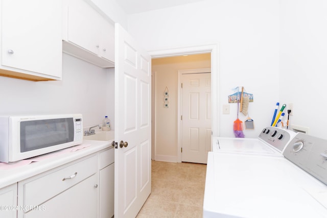 washroom featuring washing machine and dryer, cabinet space, and a sink