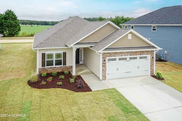 craftsman inspired home featuring a garage and a front lawn