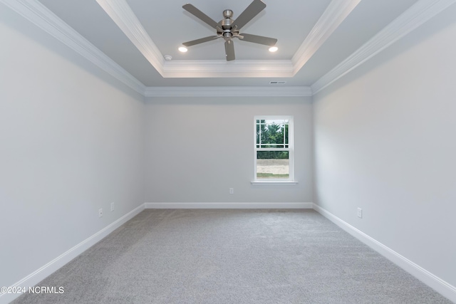 carpeted empty room with ceiling fan, crown molding, and a raised ceiling