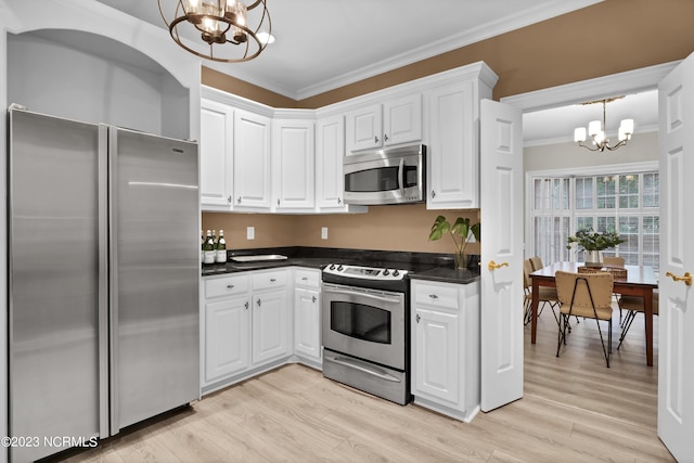 kitchen with appliances with stainless steel finishes, pendant lighting, white cabinets, and an inviting chandelier