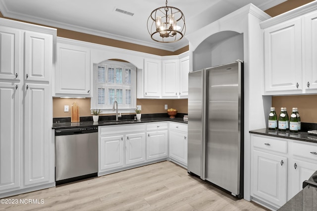 kitchen featuring pendant lighting, sink, appliances with stainless steel finishes, white cabinetry, and ornamental molding