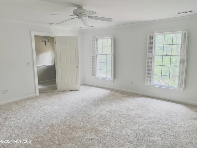 carpeted empty room with crown molding, ceiling fan, and plenty of natural light