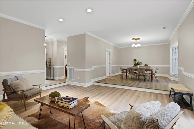 living room with hardwood / wood-style flooring, crown molding, and an inviting chandelier