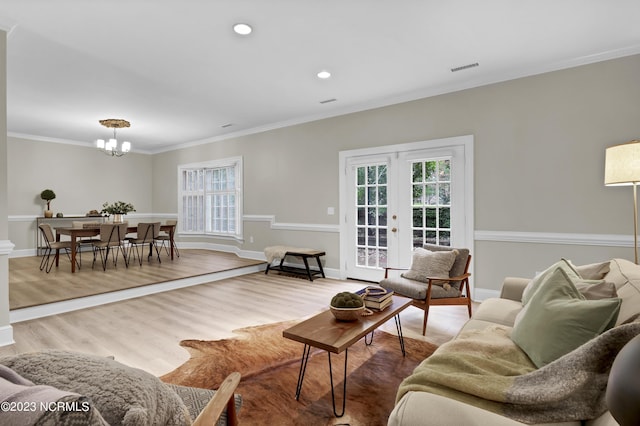 living room with hardwood / wood-style floors, a notable chandelier, ornamental molding, and french doors