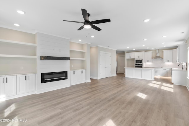 unfurnished living room featuring ceiling fan, built in features, light wood-type flooring, and a fireplace