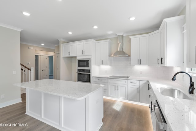 kitchen with wall chimney range hood, white cabinets, light stone countertops, and appliances with stainless steel finishes