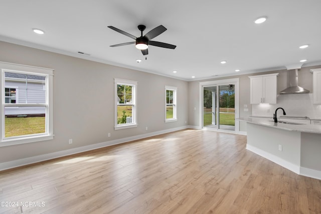 unfurnished living room featuring crown molding, sink, light wood-type flooring, and ceiling fan