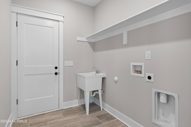 clothes washing area with light hardwood / wood-style flooring, washer hookup, and hookup for an electric dryer