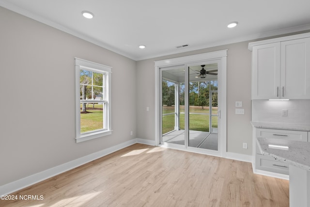 unfurnished dining area featuring light hardwood / wood-style flooring, ornamental molding, and ceiling fan