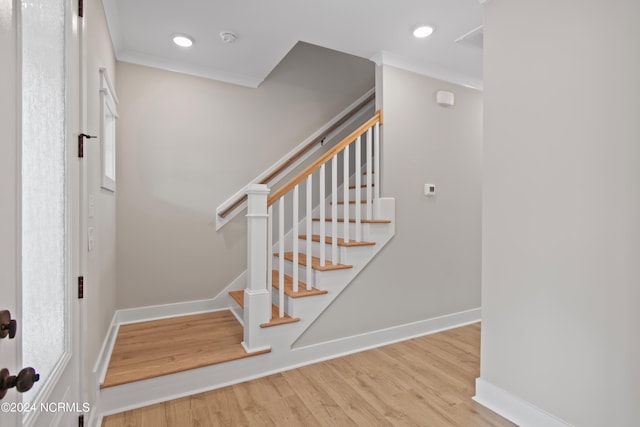 stairs with ornamental molding and hardwood / wood-style flooring